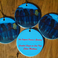 Ceramic Chistmas ornament with hand painted crooked fishing shacks and a greeting on reverse