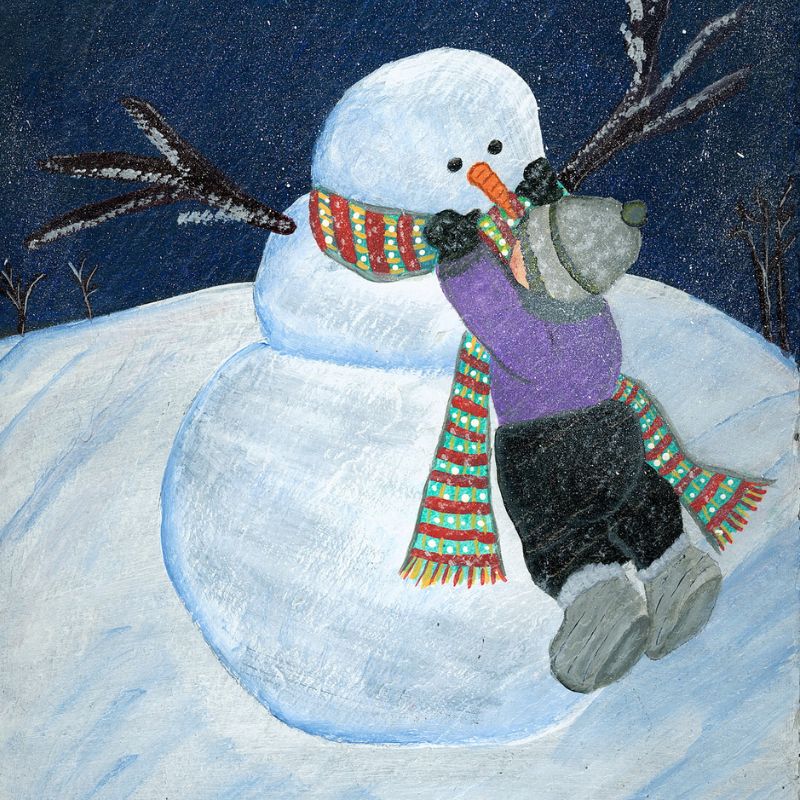 A little boy building  a snowman 
